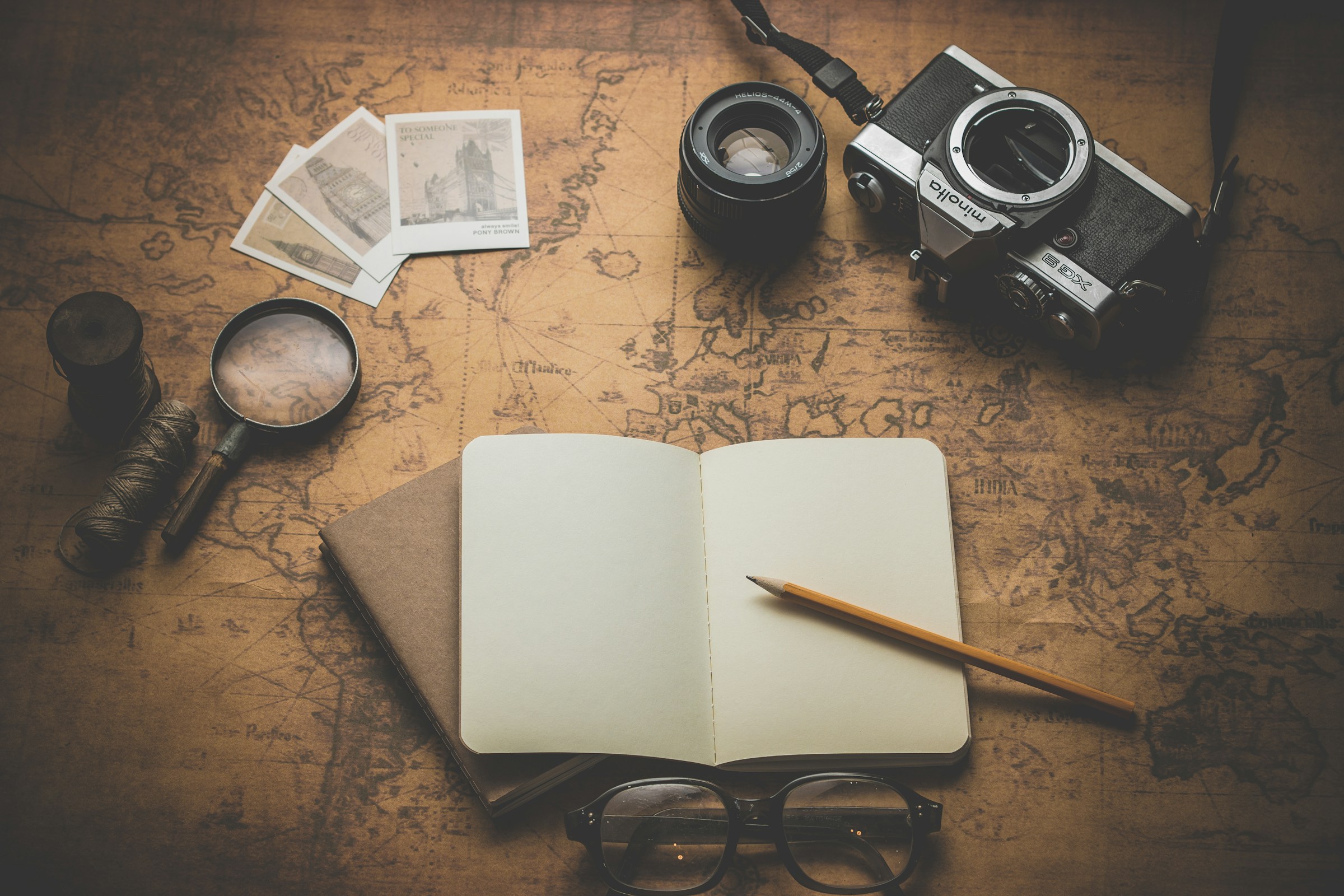 A camera, notebook and compass arranged on a travel map