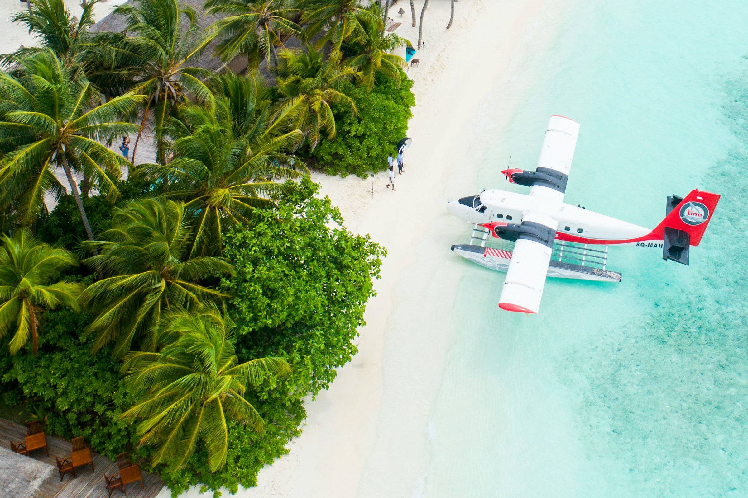 A seaplane beside a palm-fringed island and clear turquoise water