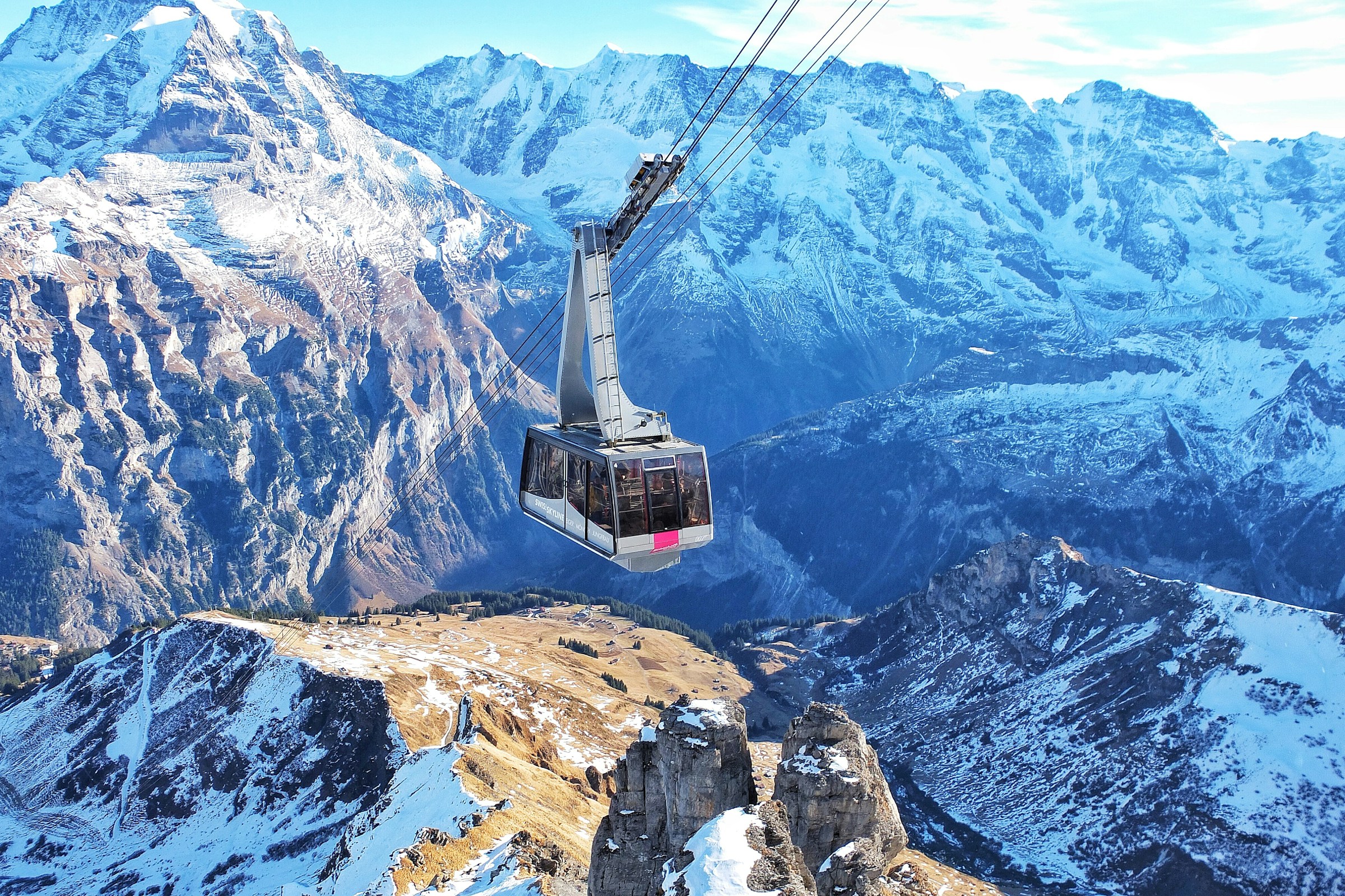 A cable car crossing a dramatic snowy alpine landscape